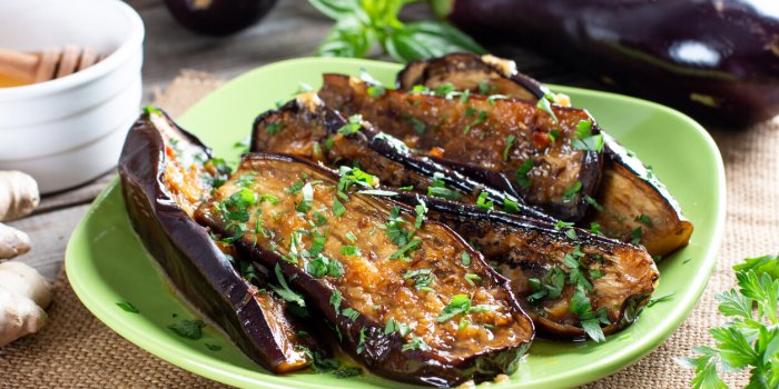 appetizer from eggplant in honey with chili parsley and lemon on a wooden table