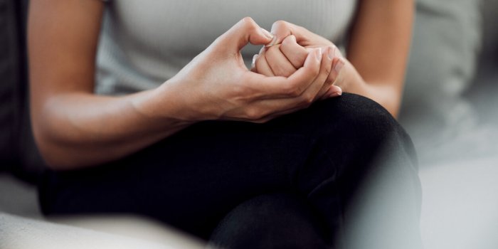 cropped shot of an unrecognisable woman sitting alone and feeling anxious while picking the skin on her nails