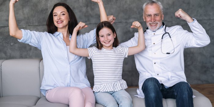 happy family doctor, smiling girl patient and mother showing strong gesture by arms, have good health and immunity, sitti...