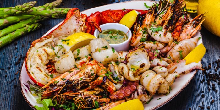 seafood platter grilled lobster, shrimps, scallops, langoustines, octopus, squid on white plate