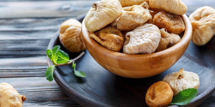 sweet dried figs in a bowl on wooden table, selective focus