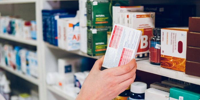 a young female pharmacist arranges medicines on the shelves of the pharmacy and makes an inventory