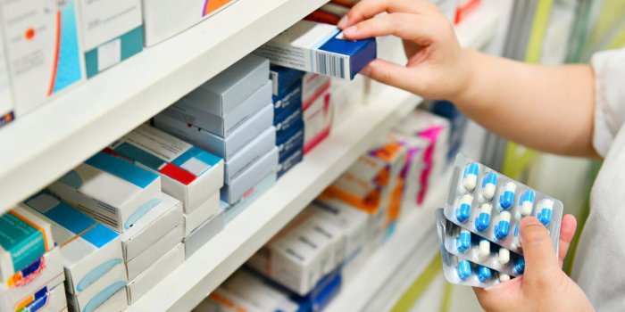 pharmacist holding medicine box and capsule pack in pharmacy drugstore