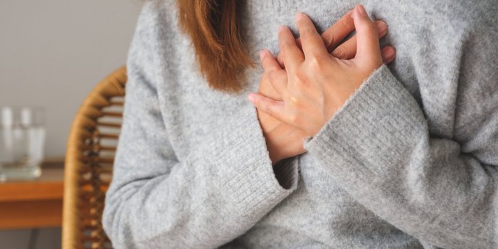 closeup image of a woman with hands on chest, sudden heart attack, suffering from chest pain