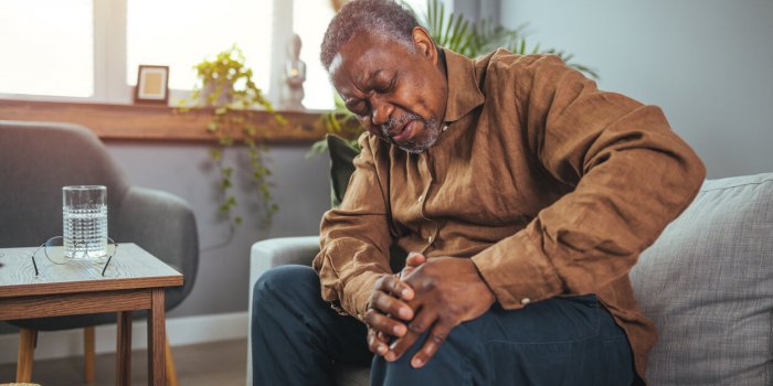 senior man holds his hands up to his knees, knee pain, arthritis, arthrosis, meniscopathy, tendonitis the concept of medi...