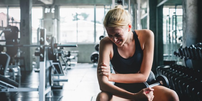 woman have accident injury and hurt at arms while workout and weight training at gym, muscle pain concept