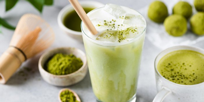 delicious vegan matcha ice latte in glass on grey stone background closeup view