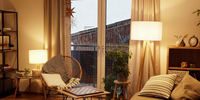 cozy scandinavian style living room with a rack, a comfortable seat and a table lamp in winter