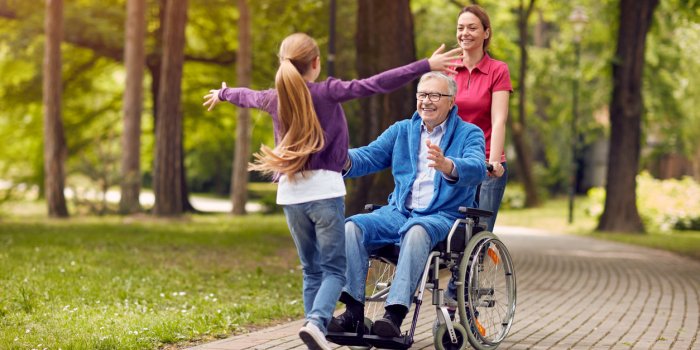 cheerful disabled grandfather in wheelchair welcoming his happy granddaughter