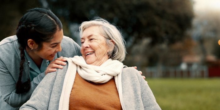 caregiver helping woman with disability in park for support, trust and care in retirement nurse talking to happy senior p...