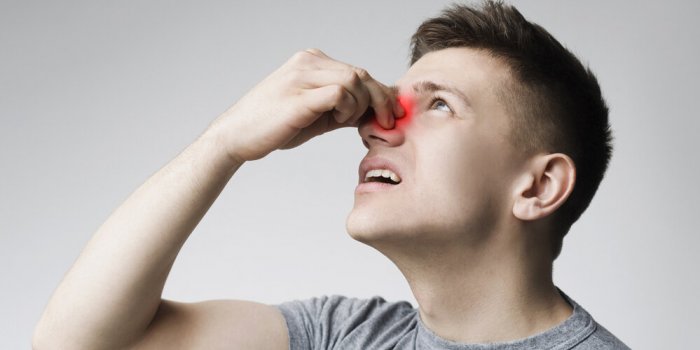epistaxis young man touching his bleeding nose, panorama, close up