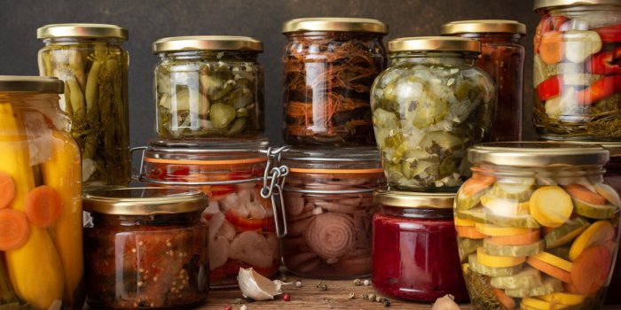 preserving vegetables for the winter, canned vegetables in jars on a wooden table against a brown wall, pickled or fermen...