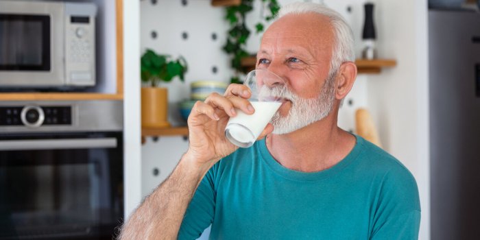 senior man drinking a glass of milk with a happy face standing and smiling handsome senior man drinking a glass of fresh ...