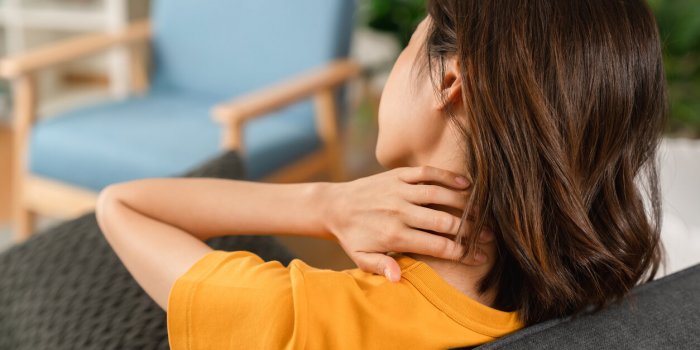 tired young woman with neck pain and sit on the sofa at home