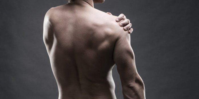 pain in the shoulder muscular male body handsome bodybuilder posing on gray background low key close up studio shot middl...