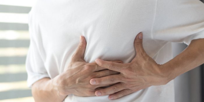 man's hands on his chest in white shirt with red spot as suffering on chest pain male suffer from heart attack,lung probl...
