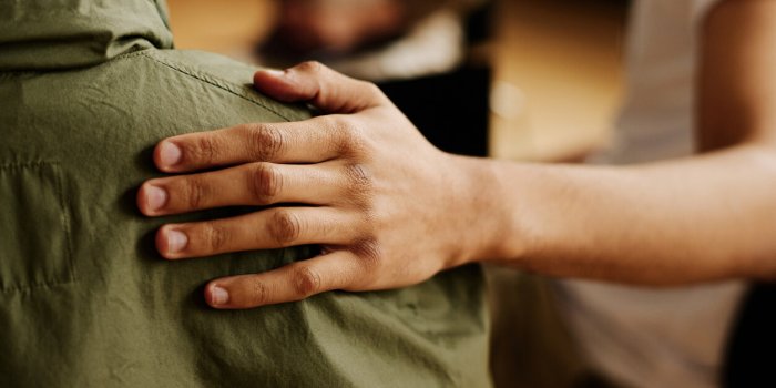 hand of young supportive man consoling his friend or one of attendants with post traumatic syndrome caused by dramatic li...