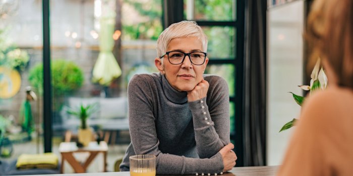 portrait of attentive modern mature woman listening to a friend at home