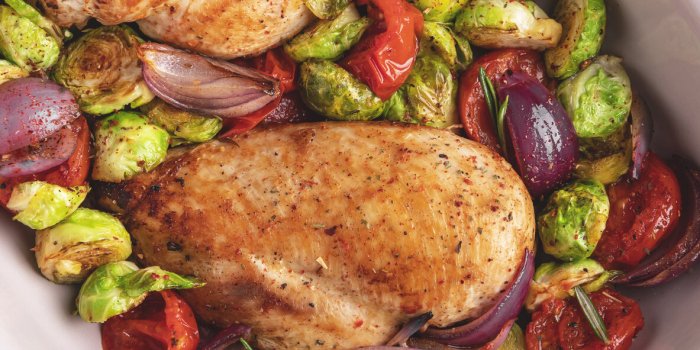 roasted chicken fillet with vegetables, brussels sprouts, onions, tomato close up