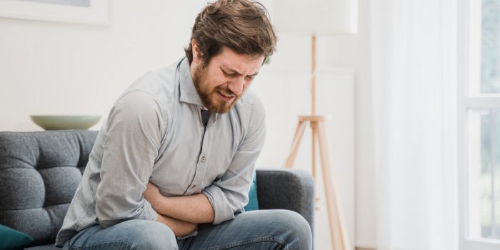 guy feeling unwell with a stomach ache while sitting at home