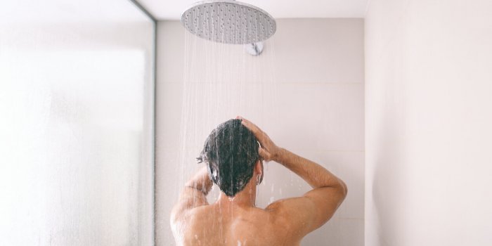 man taking a shower washing hair with shampoo product under water falling from luxury rain shower head morning routine lu...