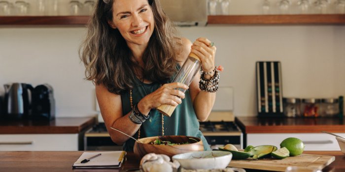 senior woman smiling at the camera while preparing some plant-based food cheerful woman following a healthy vegan recipe ...