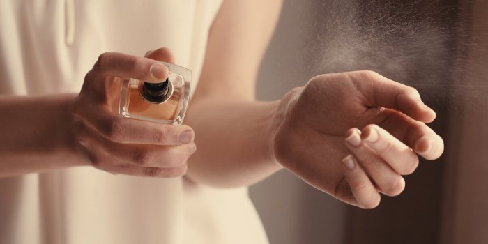 beautiful young woman with bottle of perfume at home, closeup