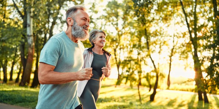 cardio training outdoors side view of caucasian grey bearded man and beautiful old woman running along summer park with s...