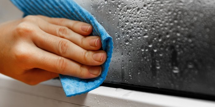 high humidity in the house hand wipes off water condensation from plastic window glass in the room home moisture