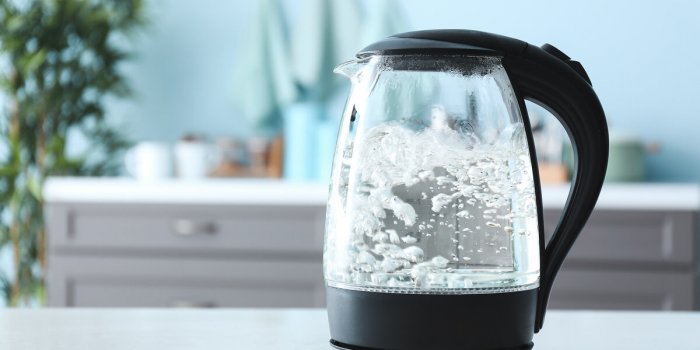 transparent electric kettle with boiling water on table in kitchen